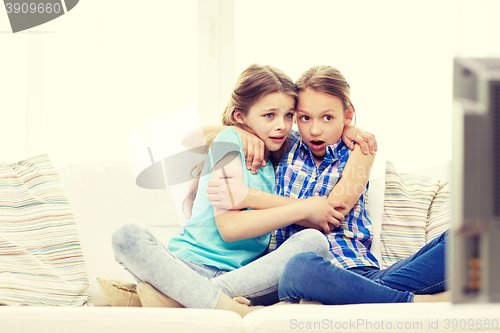 Image of scared little girls watching horror on tv at home