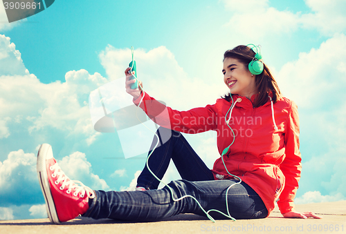 Image of happy young woman with smartphone and headphones