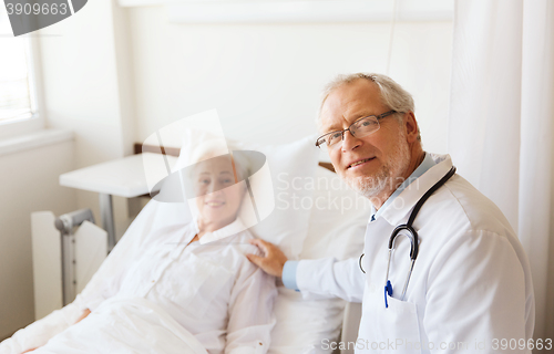 Image of doctor visiting senior woman at hospital ward