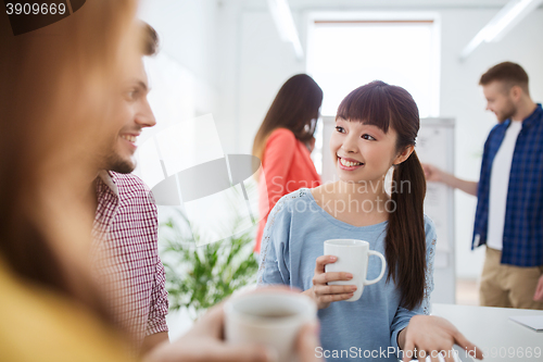 Image of happy creative team drinking coffee at office