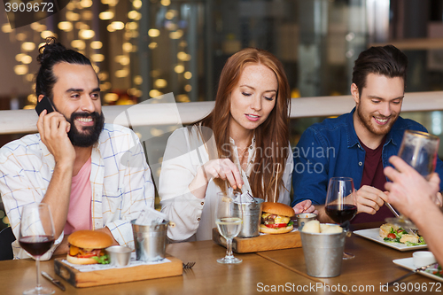 Image of man with smartphone and friends at restaurant