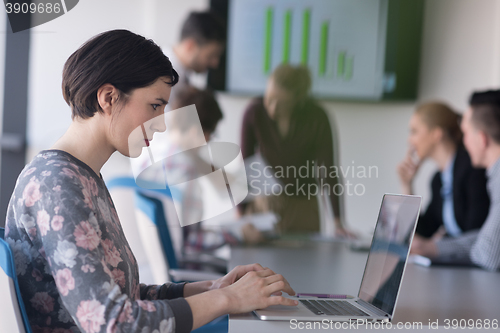 Image of young business woman at office working on laptop with team on me