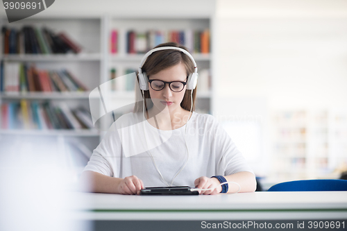 Image of female student study in library, using tablet and searching for 