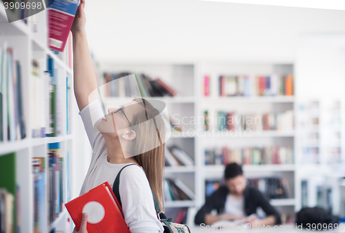 Image of famale student selecting book to read in library