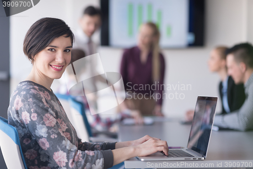 Image of young business woman at office working on laptop with team on me