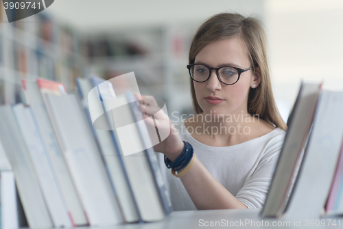 Image of portrait of famale student selecting book to read in library