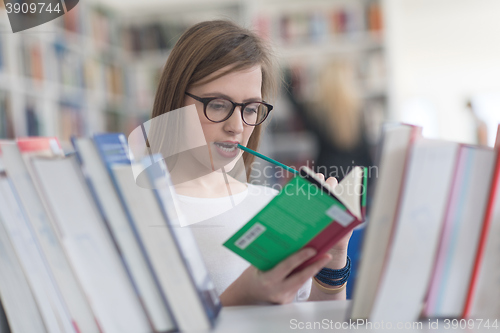 Image of portrait of famale student selecting book to read in library