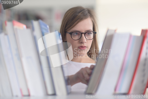 Image of portrait of famale student selecting book to read in library