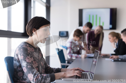 Image of young business woman at office working on laptop with team on me