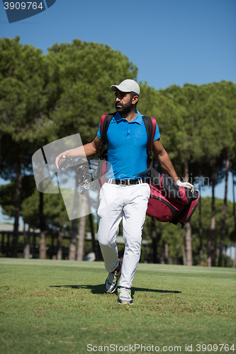 Image of golf player walking and carrying bag