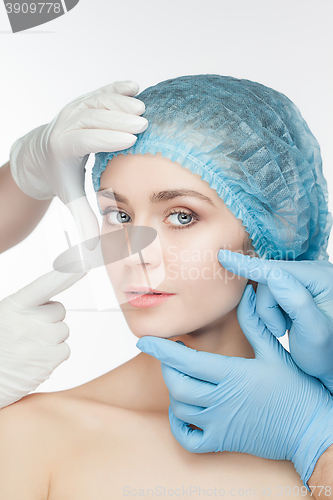Image of Plastic surgery concept. Doctor hands in gloves touching the beautiful woman face on white