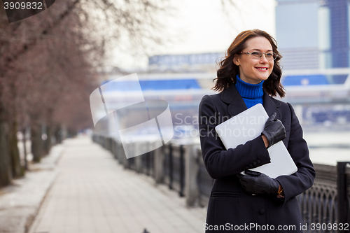 Image of smiling woman with a laptop outdoors