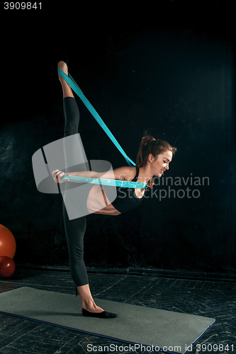 Image of The brunette athletic woman exercising with rubber tape