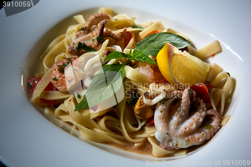 Image of Fettuccine pasta  with shrimps, lemon, baby octopus, fresh Parmesan cheese, and  oregano. 