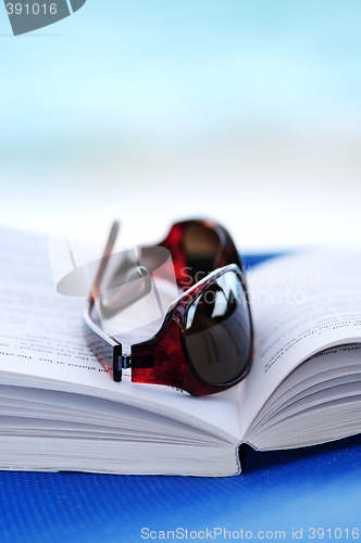 Image of Sunglasses and book on beach chair