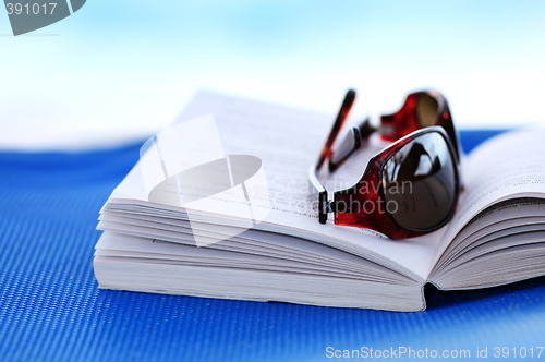 Image of Sunglasses and book on beach chair