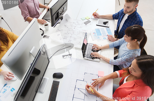 Image of creative team with computers, blueprint at office