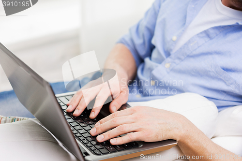 Image of close up of man typing on laptop computer at home