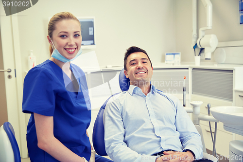 Image of happy female dentist with man patient at clinic