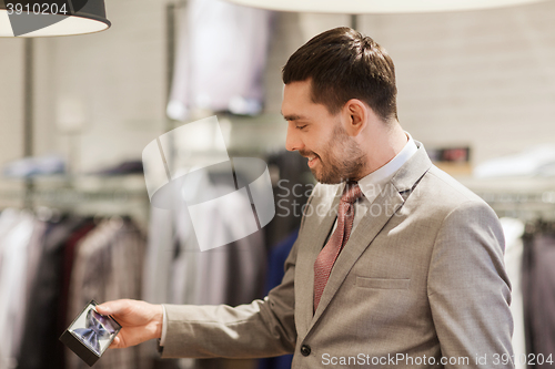 Image of happy young man choosing bow-tie in clothing store