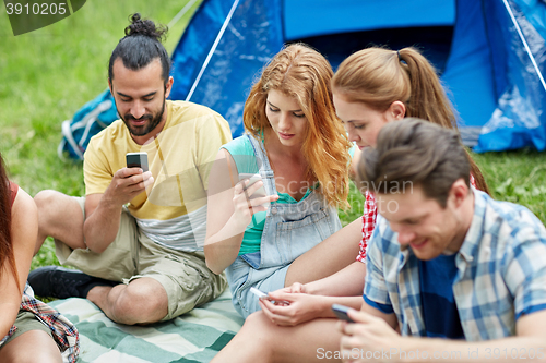Image of friends with smartphone and tent at camping