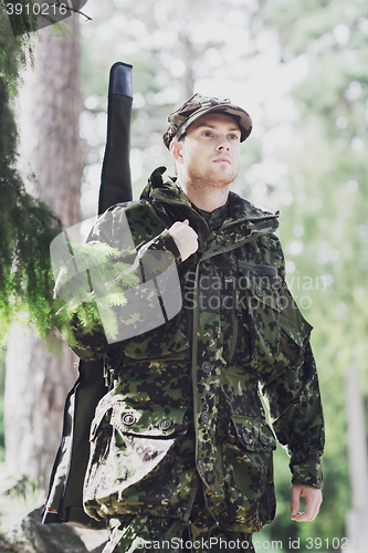 Image of young soldier or hunter with gun in forest