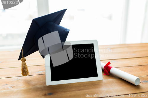 Image of close up of tablet pc with mortarboard and diploma