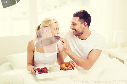 Image of happy couple having breakfast in bed at home