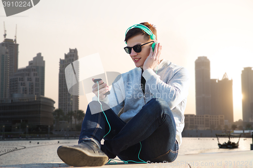 Image of happy young man in headphones with smartphone