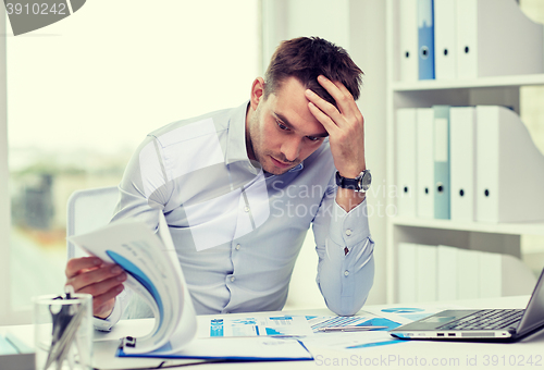 Image of stressed businessman with papers at office