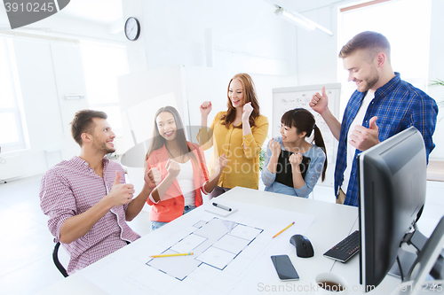 Image of happy creative team celebrating success at office