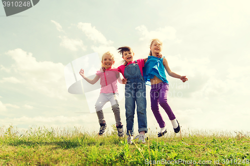 Image of group of happy kids jumping high on green field