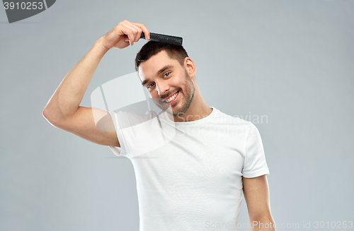 Image of happy man brushing hair with comb over gray