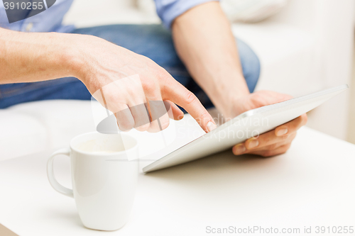 Image of close up of man with tablet pc and tea cup at home