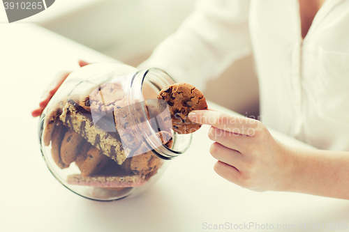 Image of close up of hands with chocolate cookies in jar