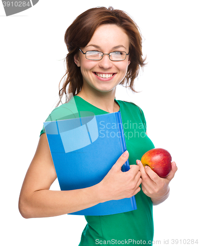 Image of Young student girl is holding book and apple