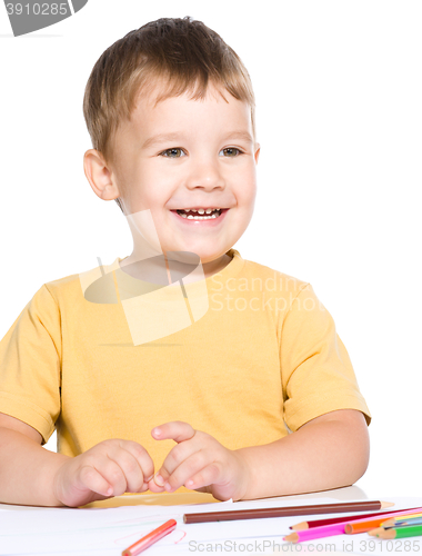 Image of Little boy is drawing using color pencils