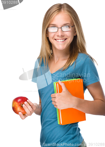 Image of Young student girl is holding book and apple