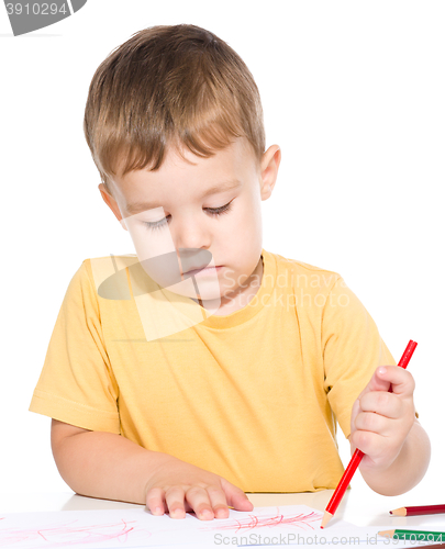 Image of Little boy is drawing using color pencils