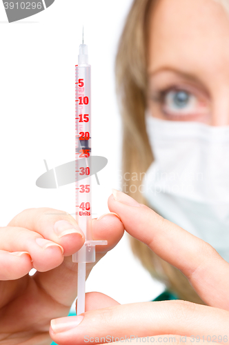 Image of Young nurse is preparing syringe for injection