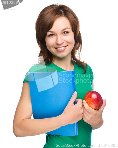 Image of Young student girl is holding book and apple