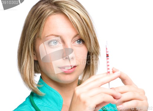 Image of Young nurse is preparing syringe for injection