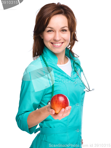 Image of Young lady doctor is holding a red apple