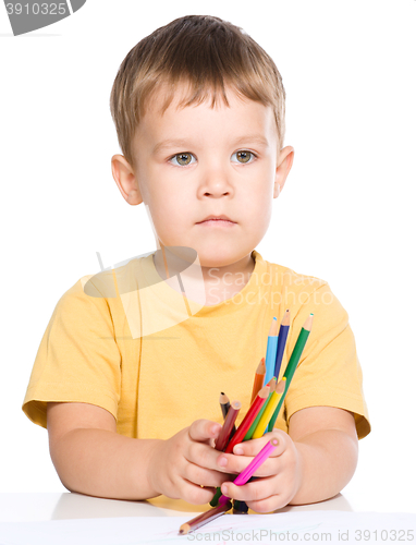 Image of Little boy is holding color pencils