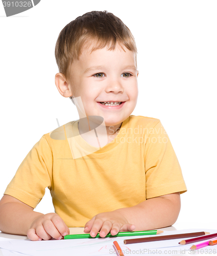 Image of Little boy is drawing using color pencils