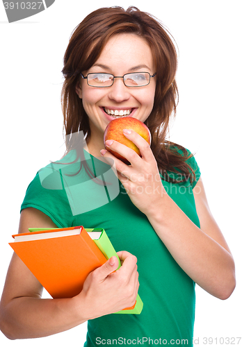 Image of Young student girl is holding book and apple