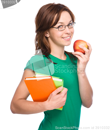 Image of Young student girl is holding book and apple