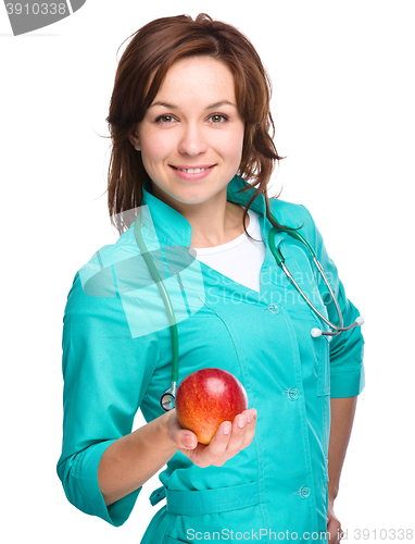 Image of Young lady doctor is holding a red apple
