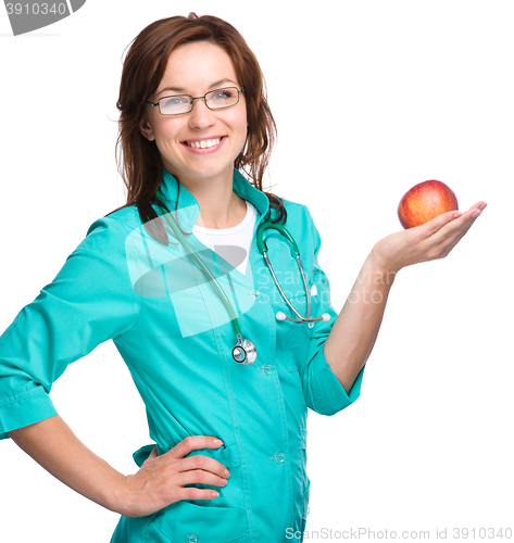 Image of Young lady doctor is holding a red apple
