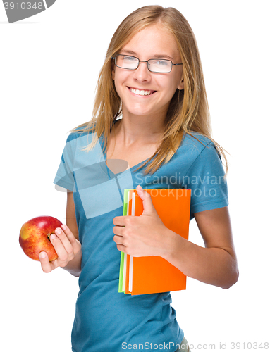 Image of Young student girl is holding book and apple